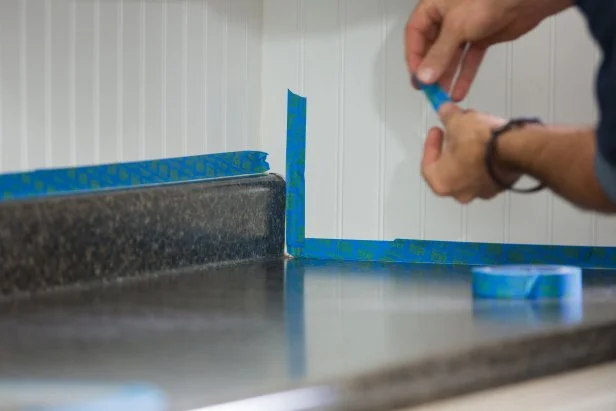 Now that the countertop is prepped for painting, you’ll want to protect everything that’s not going to get primed and painted. Use painter’s tape to protect the sink and walls.