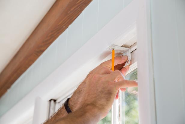 Locate your bracket locations on the top of the inner window casing and about 1/2 inch away from the windowpane. Hold each bracket in place and mark the screw holes with a sharp pencil.