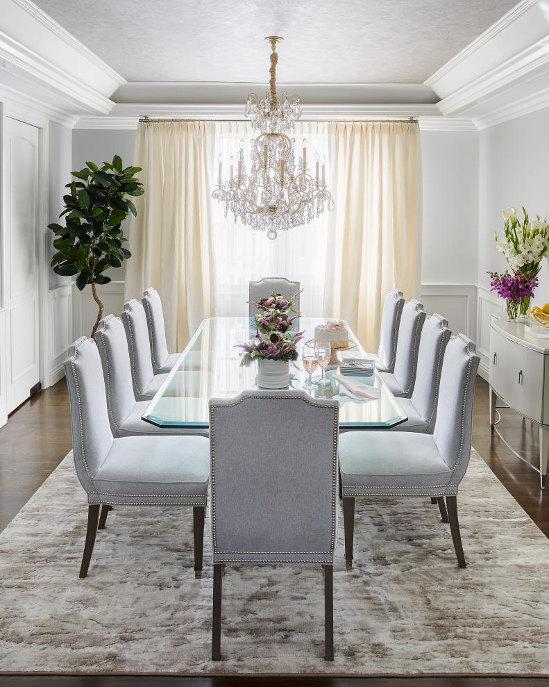 Grand Crystal Chandelier Hangs Above Glass Dining Table With 10 Chairs