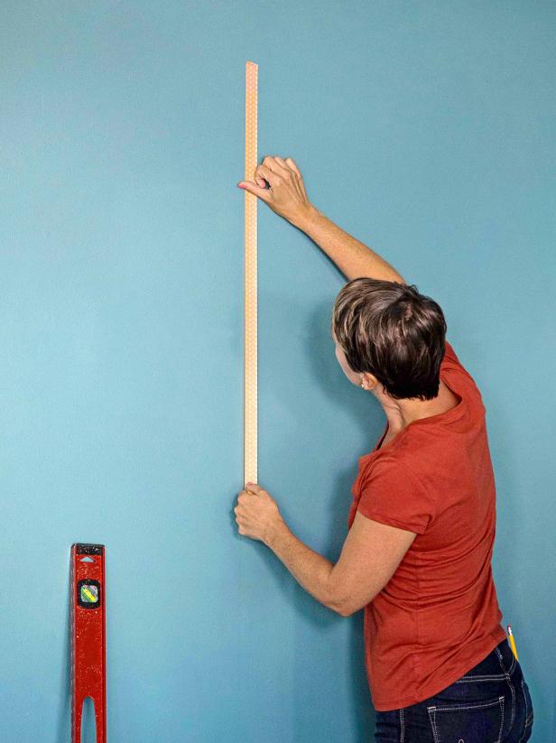 Use a stud finder to locate studs on the wall where the back of the cabinet will go. Use a level and a pencil to mark the stud. Run a piece of washi tape vertically to easily locate the stud when attaching the frame.