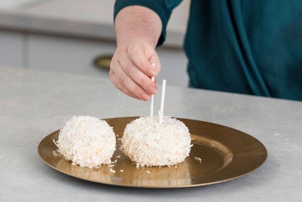 Stick two lollipop sticks into the center of the larger cheese ball. This will support the smaller cheese ball on top.