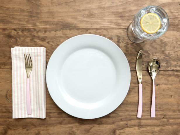 A Wooden Table With a White Plate and Flatware