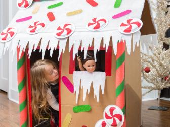 A Young Child Playing in a Cardboard Gingerbread Playhouse