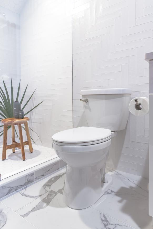 White Toilet Next to Shower With Wood Stool