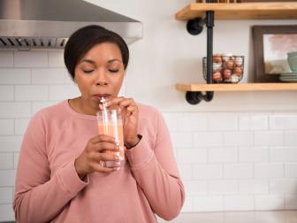 woman drinking smoothie from a glass in kitchen