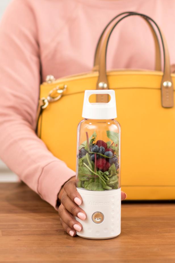Woman holding portable smoothie blender with purse