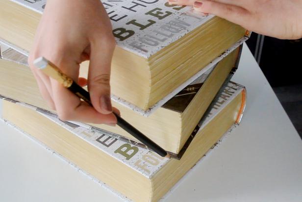 After stacking the decorative book boxes in your chosen design, mark where the books overlap. Flip the entire stack and mark where they overlap on the bottom of the books.