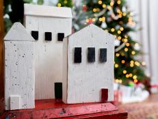 Three Painted Wooden Houses Displayed in Front of Christmas Trees