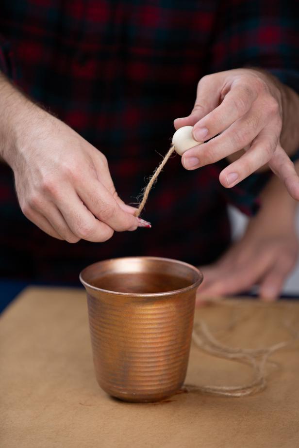 Then, hot glue the other end of the twine to the inside of the pot so that the bead hangs just below the lip.