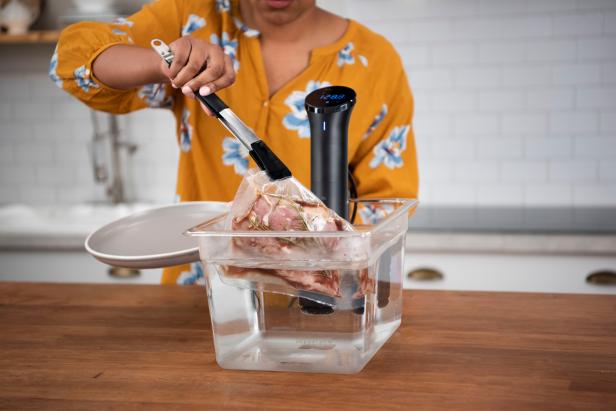 Woman taking meat out of water bath with sous vide cooker