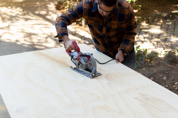 Using a saw, cut the plywood at the marked lines.