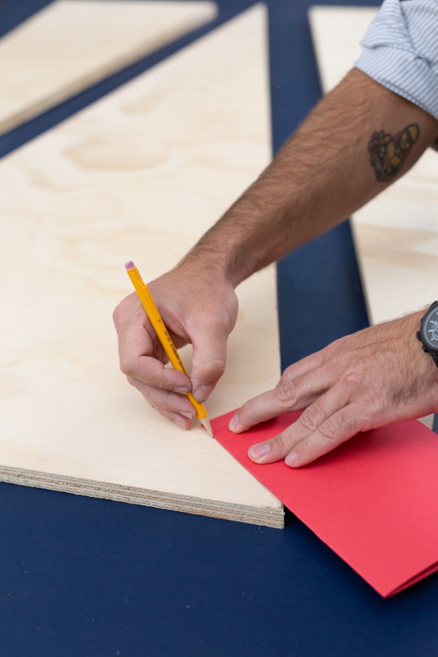 Using a pencil and a piece of folded paper, mark the edges for the Christmas tree on the plywood.