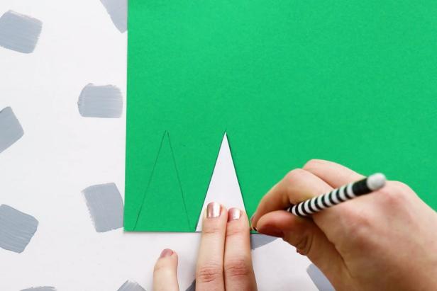 Begin by cutting triangles of various sizes from scrap paper. Next, trace a triangle twice on green scrapbook paper and cut out.