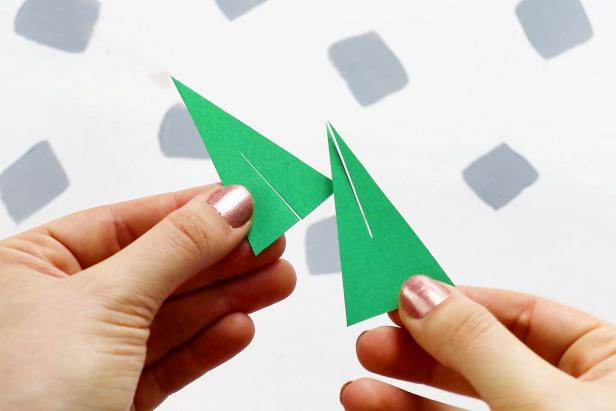 On one triangle, cut a line halfway up from the bottom. On the other triangle, cut a line halfway down from the top. Slot them together to form a Christmas tree.