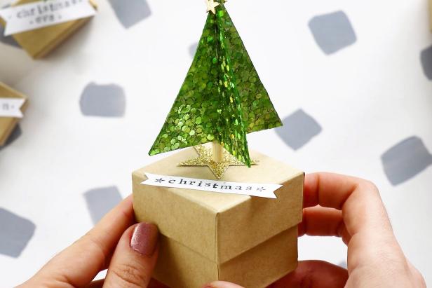 Gather 24 small gift boxes from the party store. Hot glue a tree to the top of each one then use a glue stick to attach the number banner. Use a larger box for Christmas Day.