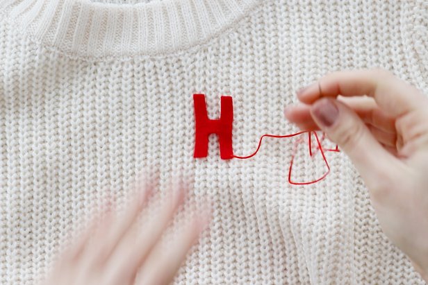 Embellish a plain white sweater with a couple pieces of felt to make a cute Santa-inspired sweater for the holidays.