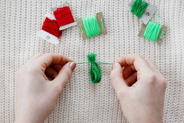 Embellish a plain white sweater with a red and green tassels to make a cute and festive sweater for the holidays.