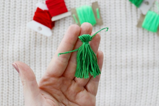 Embellish a plain white sweater with a red and green tassels to make a cute and festive sweater for the holidays.