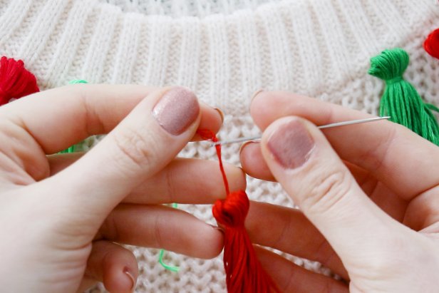 Embellish a plain white sweater with a red and green tassels to make a cute and festive sweater for the holidays.