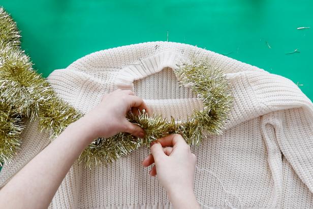 Embellish a plain white sweater with metallic tinsel to make a cute and festive sweater for the holidays.