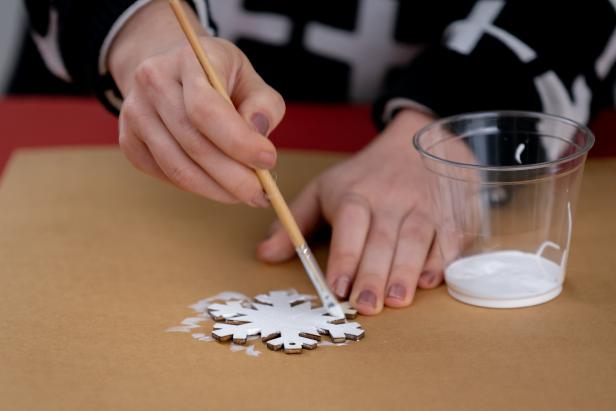 Then, paint your wooden snowflake white, making sure to paint the edges as well. You may have to paint multiple coats to get an even finish.