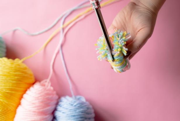 Using a sharp pair of scissors, cut around the pom-pom maker down the middle of each arm.