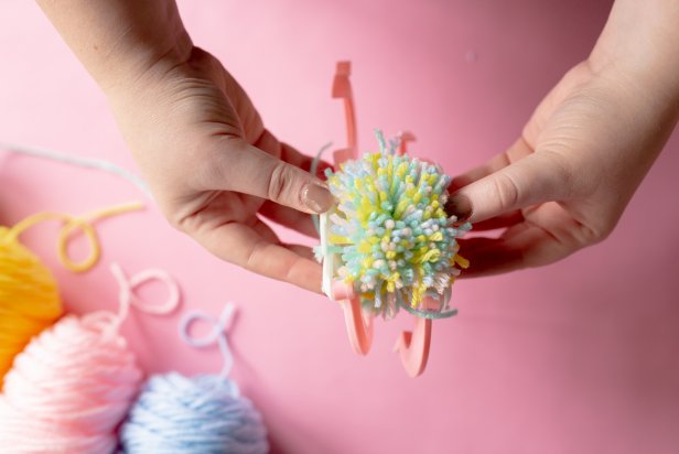 Open up the arms of the pom-pom maker to reveal your fluffy creation. Pull apart the maker from the center to release the pom-pom.