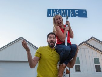 HGTV Drew Scott helps Rock The Block Season One winner Jasmine Rock climb up the street sign that announces Roth as the winner of Season One, as seen on Rock the Block.