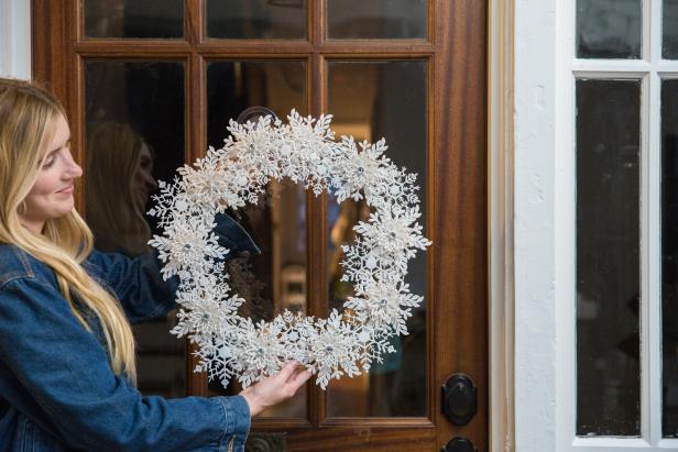 A Snowflake Wreath Being Hung On a Door