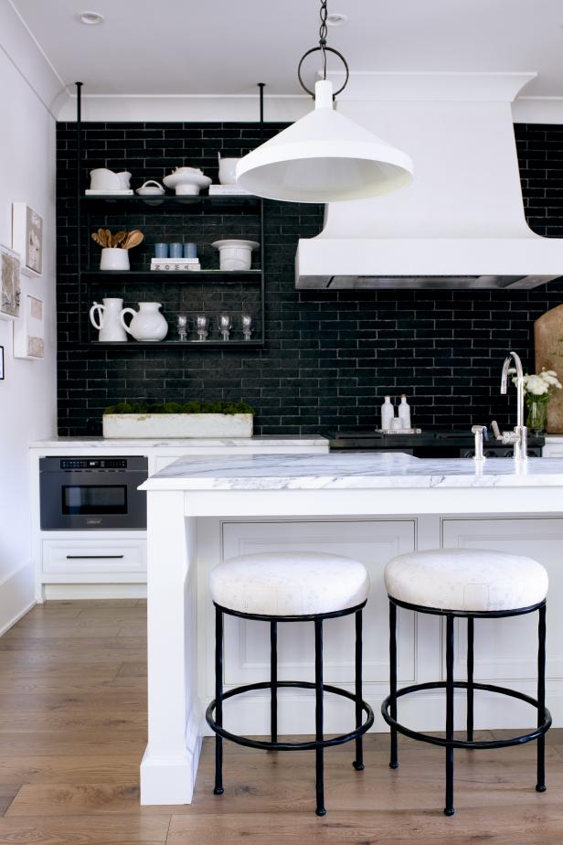A sophisticated take on the most utilitarian of spaces, this black and white kitchen uses black subway tiles for a chic take on the usual white tile and open shelving to give this small space a sense of expansiveness.