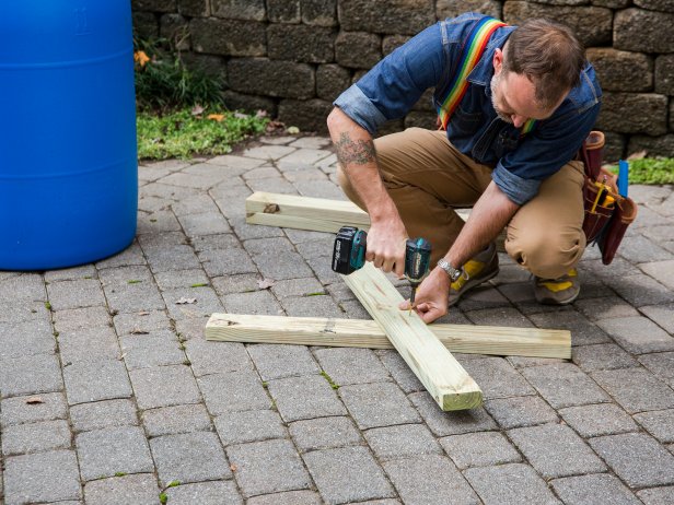 Make an X shape that’s 2’ wide at the top and bottom using two of the 3’ boards. Attach the boards in the center of the X using 2” exterior-grade screws.