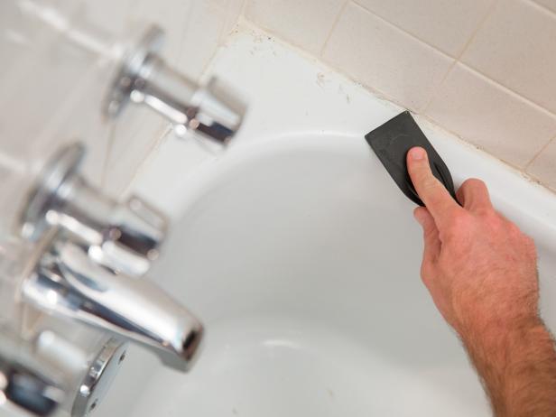 Start by scraping as much of the old caulk away as possible with a plastic putty knife. Avoid using a metal scraper if possible, as it could damage your porcelain.