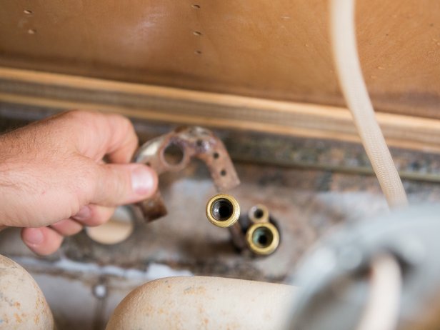 Unscrew the mounting nuts from the threaded ends of the faucet and handles.