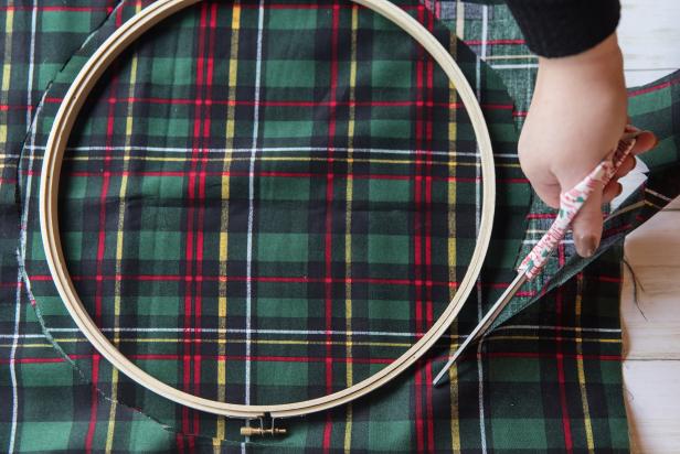Begin by placing the embroidery hoop on top of the fabric. Using the hoop as a guide, cut out the fabric, about an inch away from the outer edge, to achieve a circular shape.