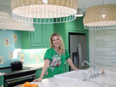 After the renovation, Grace posese in the fully remodeled kitchen, which features a custom backsplash created with pages from Mandy's grandmother's gardening books, wallpaper made from a blown up print of Alex's parents' family restaurant's menu, and a fully functional island complete with a sink, oven, and trash compactor as seen on One of a Kind.