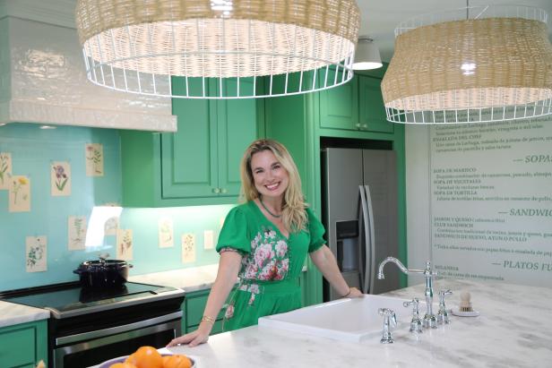 After the renovation, Grace posese in the fully remodeled kitchen, which features a custom backsplash created with pages from Mandy's grandmother's gardening books, wallpaper made from a blown up print of Alex's parents' family restaurant's menu, and a fully functional island complete with a sink, oven, and trash compactor as seen on One of a Kind.