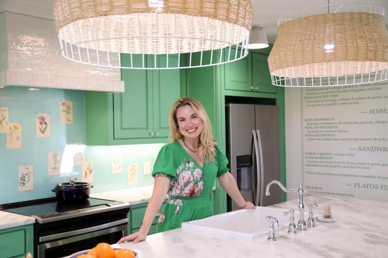After the renovation, Grace posese in the fully remodeled kitchen, which features a custom backsplash created with pages from Mandy's grandmother's gardening books, wallpaper made from a blown up print of Alex's parents' family restaurant's menu, and a fully functional island complete with a sink, oven, and trash compactor as seen on One of a Kind.