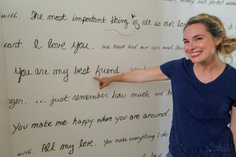 Grace Mitchell shows off the custom wallpaper she created from Charlie and Erin Schultz's love letters to each other.