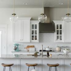 Kitchen With White Cabinets, Marble Counters and Glass Light Fixtures