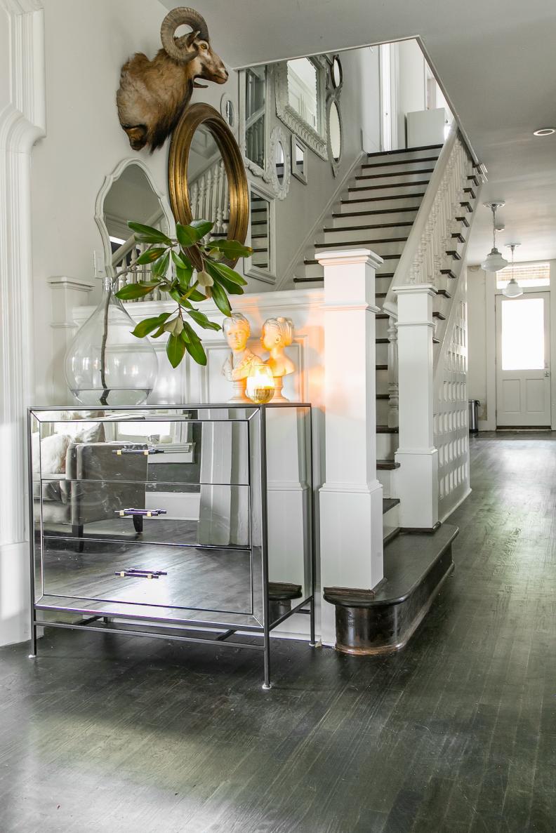 Plenty of reflective surfaces in a mirrored dresser and mirrors of different sizes really open this transitional hallway space up and keep things light, airy and glam.