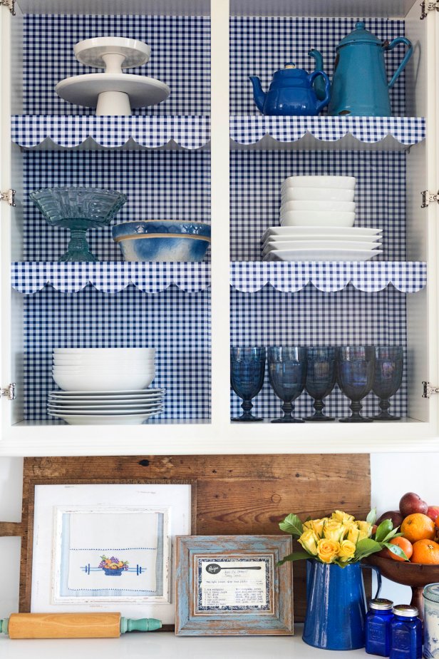 Give your kitchen a big boost of cozy cottage style by inexpensively lining the shelves with gingham shelf paper and framing family recipes and a hand-me-down tea towel as art.
