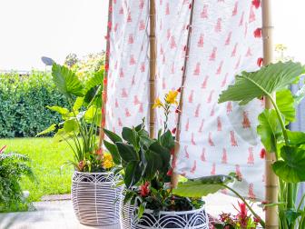 Stylish basket planters paired with repurposed shower curtains and bamboo poles make a chic privacy wall.
