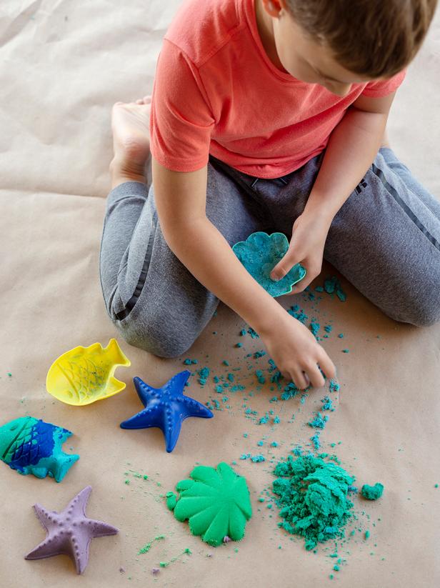 Little boy playing with colorful sand.