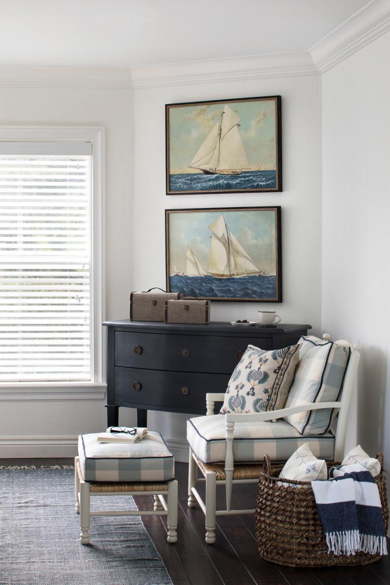Framed Art Of Ships Hangs Above Cushioned Armchair And Dark Dresser