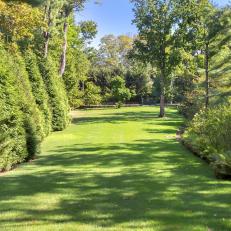 Greek Revival Home Features Lush Green Lawn With Trees