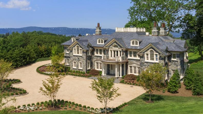 Aerial View of a Stone Mansion with Off White Finishes and a Large Driveway