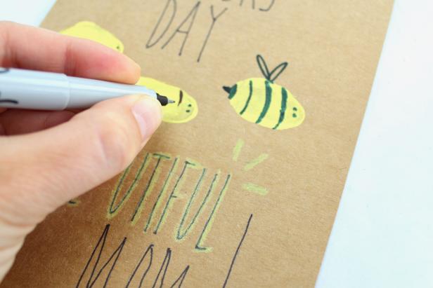 Draw designs on thumbprints so they resemble bumblebees.