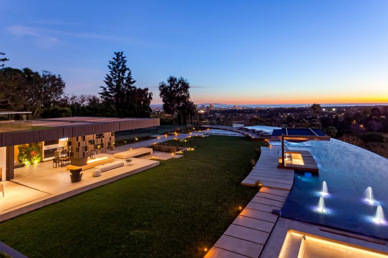 Fountains in Curved Swimming Pool Outside Contemporary Home at Night