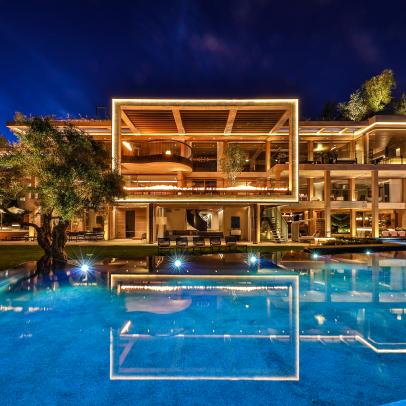 Swimming Pool at Nighttime Reflects Lights From Contemporary Mansion