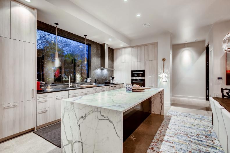 A Large Window Hangs Above The Sink With Rugs On The Kitchen Flooring